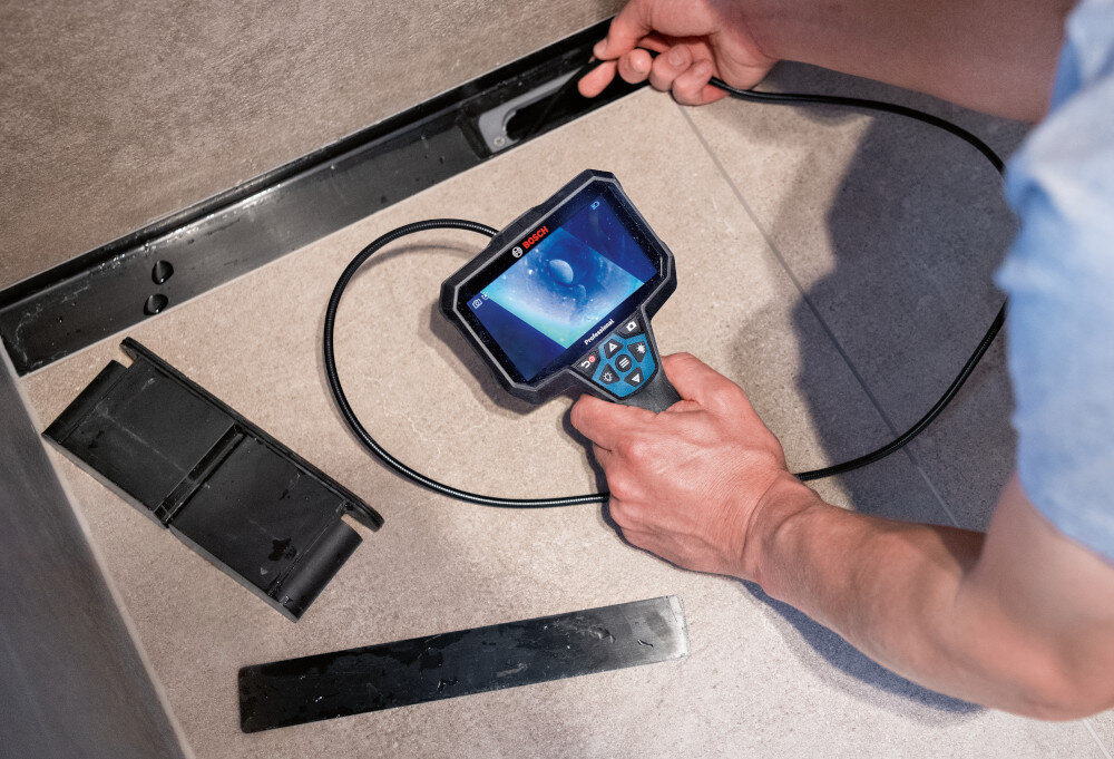 Kamera inspekcyjna BOSCH GIC 12V-5-27C 0601241401 pomieszczenie osoba sprawdza instalację w podłodze obsługuje transmisję danych przez USB-C karty micro SD duża elastyczność w zestawie karta 32 GB i kabel USB-A/USB-C