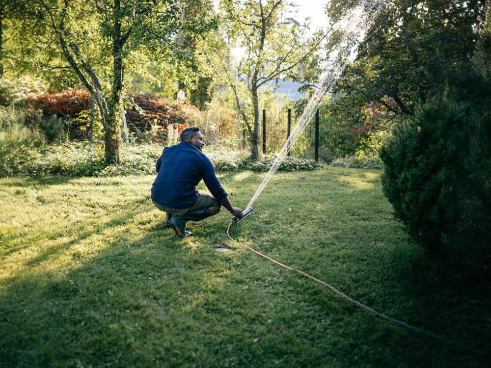 Zraszacz FISKARS 1070832, przepływ, dysze, delikatny, oszczędność, mężczyzna ustawia zraszacz na daną strefę trawnika w ogrodzie