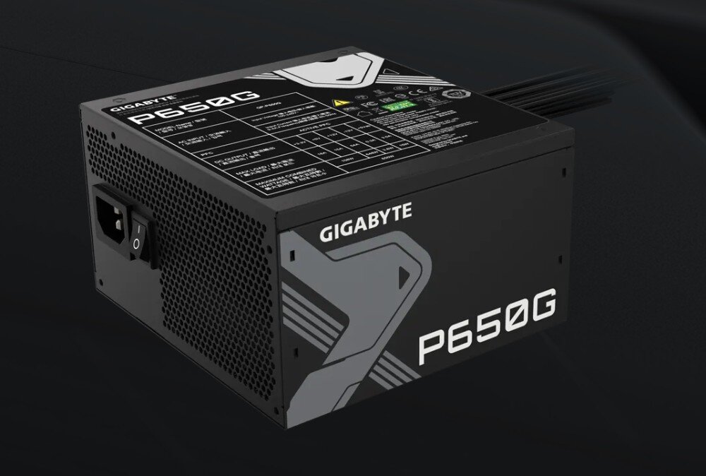 Zasilacz GIGABYTE P650G Zbliżenie na tabliczkę znamionową urządzenia zawierającą tabelę z parametrami napięć oraz logotypy certyfikatów bezpieczeństwa