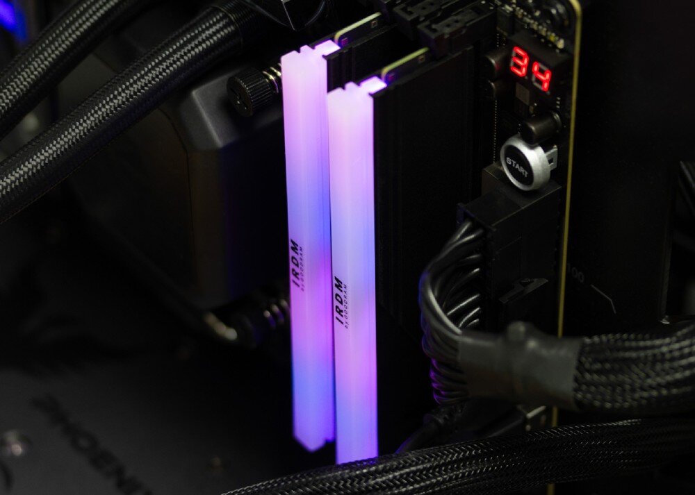 Pamięć RAM GOODRAM IRDM RGB Dwa moduły pamięci zamontowane w płycie głównej, emitujące miękkie światło w odcieniach fioletu i błękitu, widoczne elementy chłodzenia cieczą
