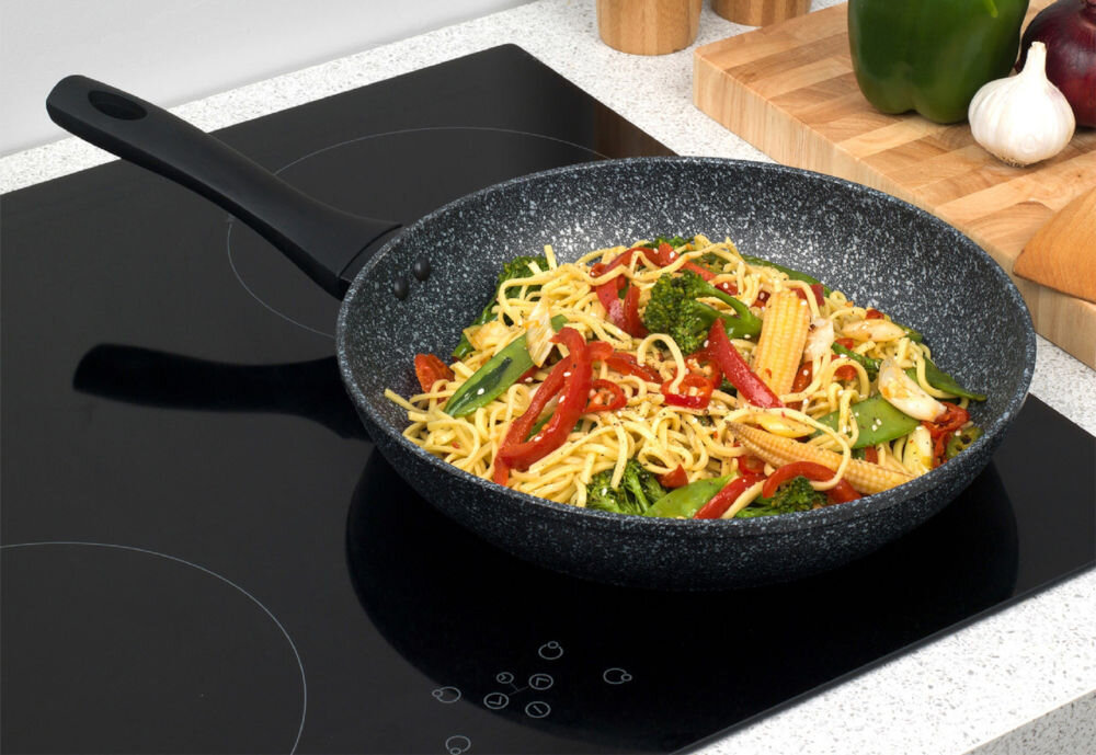 Patelnia SALTER Megastone BW05747S 28 cm Beztłuszczowa do każdej kuchni ciemna patelnia stoi na płycie potrawa z makaronem na patelni czarny uchwyt