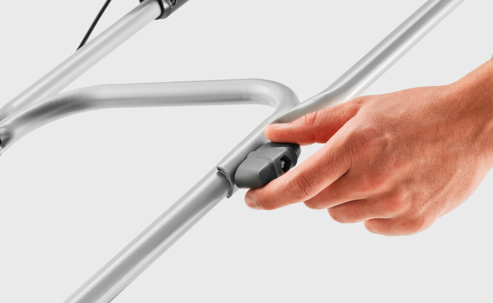 Kosiarka akumulatorowa KARCHER LMO 2-18 1.445-400.0 zbliżenie na pokrętło do regulacji uchwytu jasne tło regulowany uchwyt prowadzący dopasowanie do indywidualnej wysokości użytkownika piankowa powłoka uchwytu komfort pewność chwytu wbudowany uchwyt transportowy waga około 10,6 kg bez akcesoriów