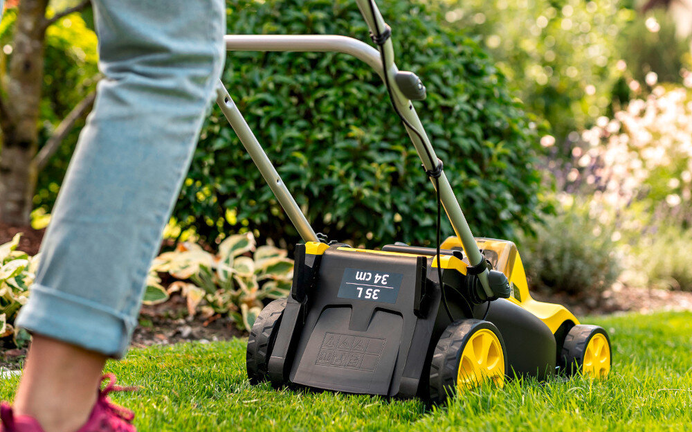 Kosiarka akumulatorowa KARCHER LMO 3-18 Battery Set 1.445-411.0 trawnik osoba kosi trawę widok od tyłu w tle drzewa kwiaty platforma bateryjna KARCHER Battery Power 18 V silnik bezszczotkowy wysoka wydajność pracy prędkość obrotowa do 3500 obr./min do trawników o powierzchni do 350 m²