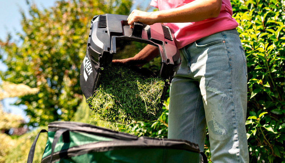 Kosiarka akumulatorowa KARCHER LMO 3-18 Battery Set 1.445-411.0 ogród osoba opróżnia worek do kompostownika w tle dom niebo krzewy drzewa tekstylny kosz o pojemności 35 litrów elastyczna konstrukcja pozwala na szybkie złożenie do niewielkich rozmiarów