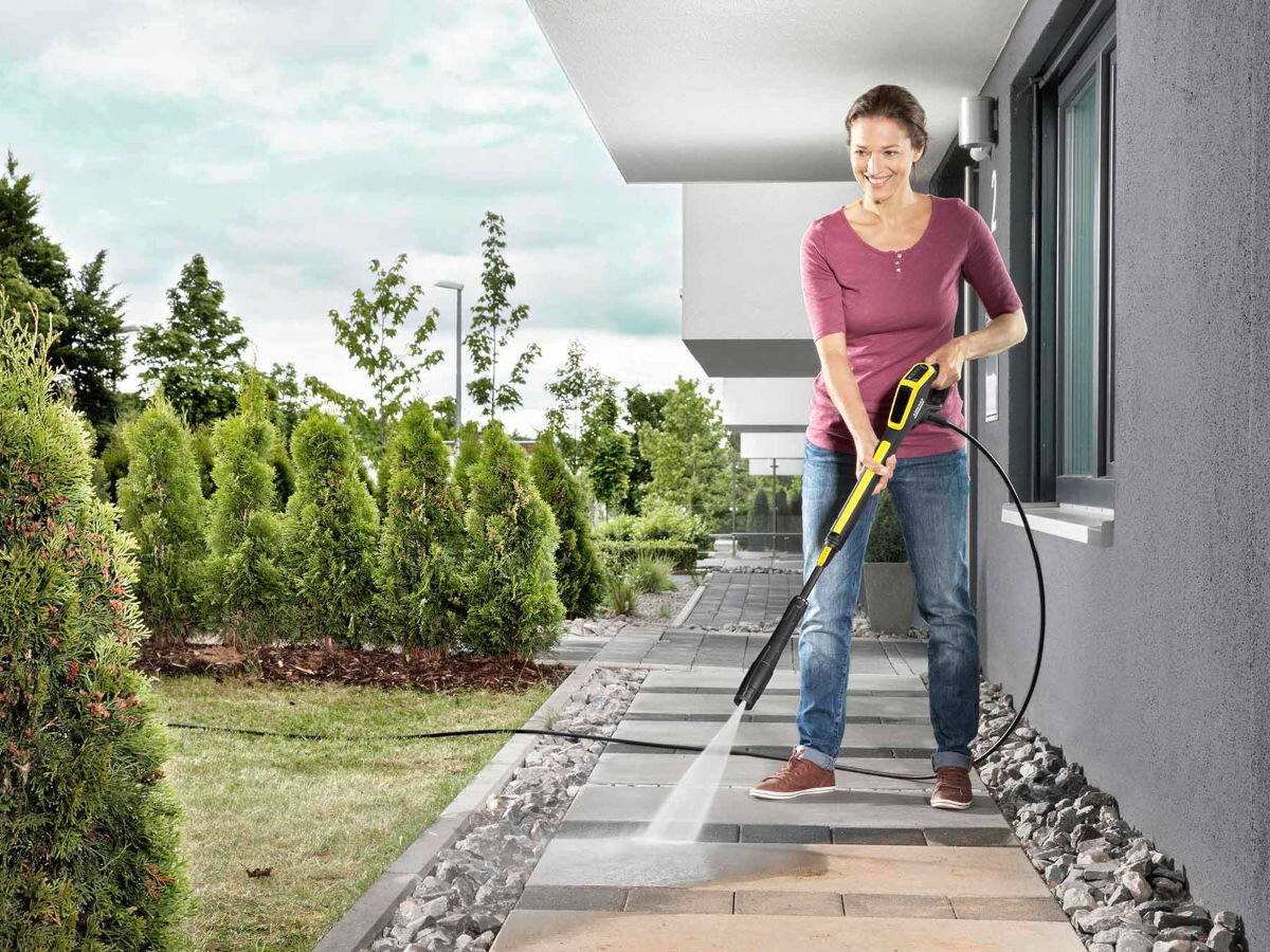 Pistolet KARCHER 2.644-327.0, komfort, porządek, czystość, woda, w tle ogród i dom, kobieta czyści pistoletem posadzkę domu
