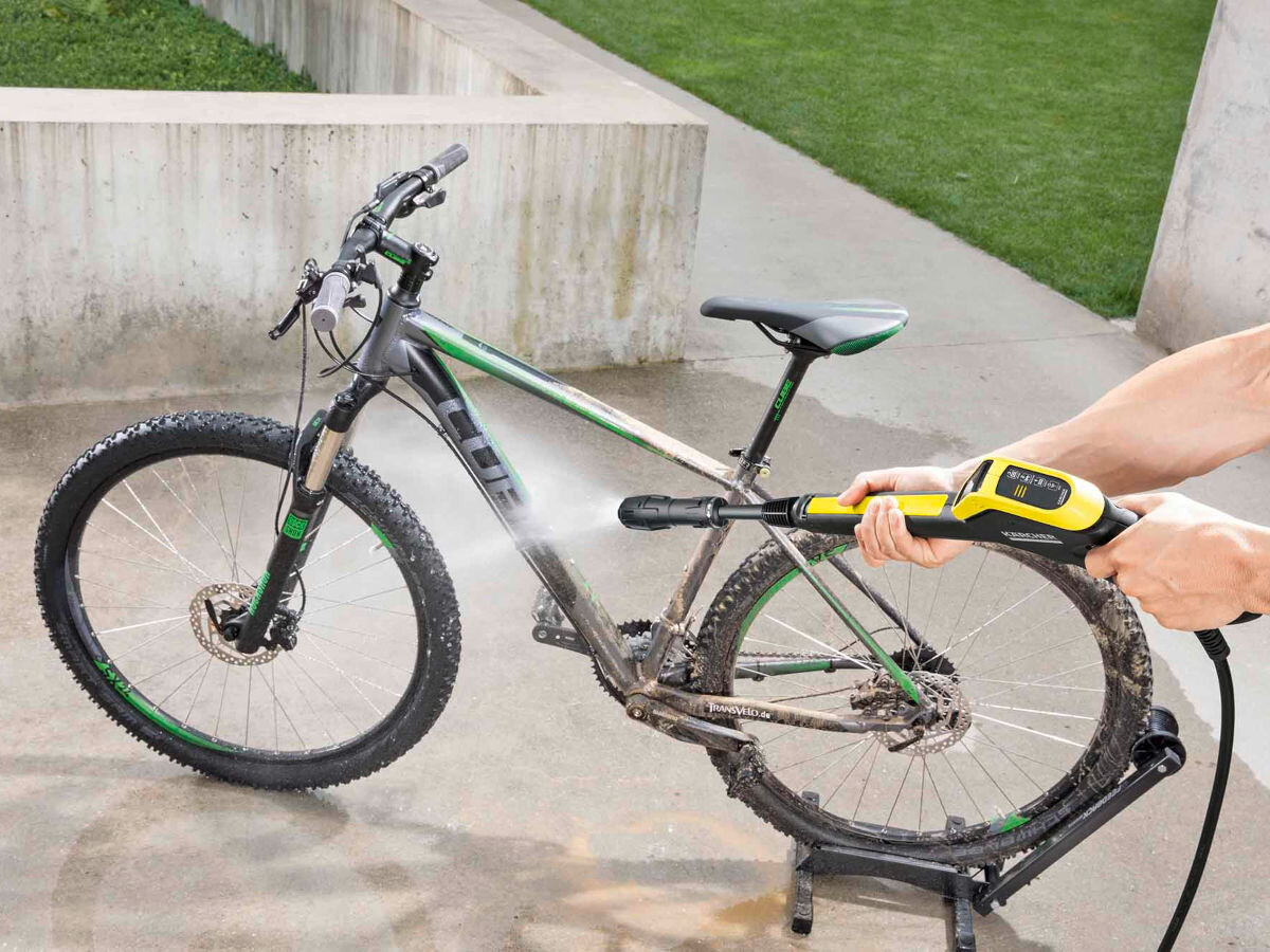 Pistolet KARCHER 2.644-327.0, zgodny, full control, power control, Kompatybilny, osoba trzyma pistolet w dłoniach myjąc nim rower