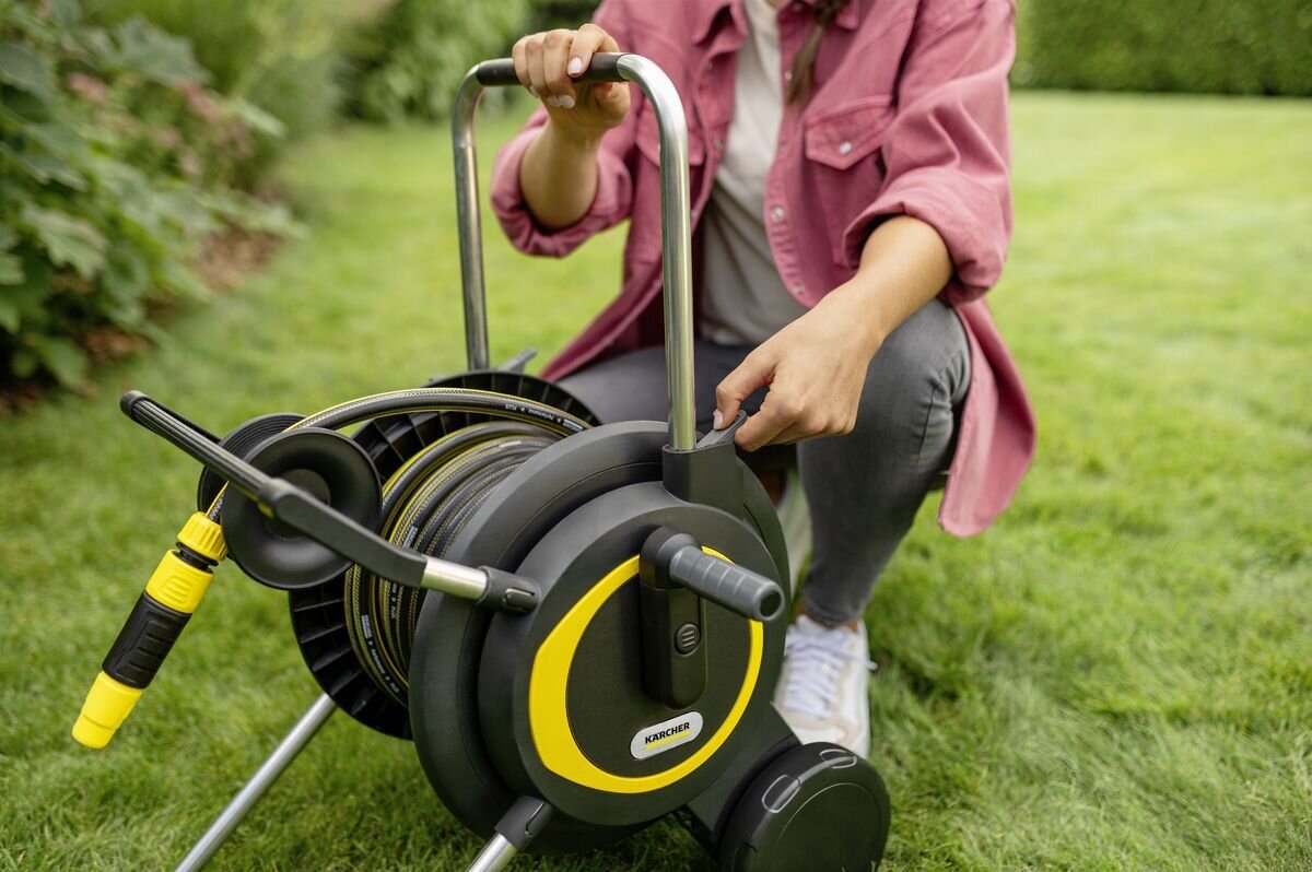 Wózek KARCHER z wężem HT 4.20 2.645-366.0, korba, prowadnica, zwijanie, wygoda, Kobieta obsługuje mechanizm wózka na wąż.