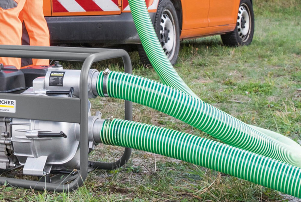Wąż odpływowy KARCHER Professional L 10m 2.645-341.0 widok z bliska na pompę do brudnej wody Kärcher, z dwoma zielonymi wężami na pierwszym planie