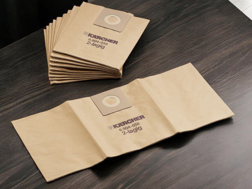 Worek do odkurzacza KARCHER 6.904-337.0 (300 sztuk) rozłożona torebka i torebki na stosie na ciemnym blacie