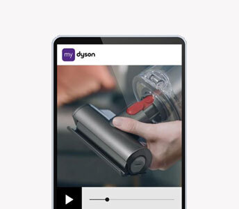 Na ekranie urządzenia widoczny jest obraz przedstawiający rękę trzymającą element odkurzacza. W górnej części ekranu znajduje się logo \'my dyson\'.