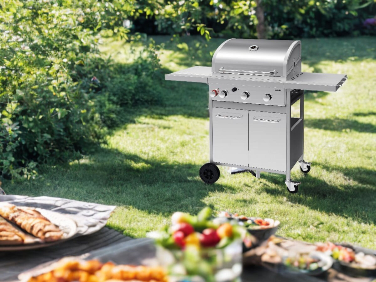 Grill gazowy LUND 99654, ogród, relaks, grillowanie, wypoczynek, w tle ogród, grill stojący w pełni złożony, na pierwszym planie przygotowane posiłki