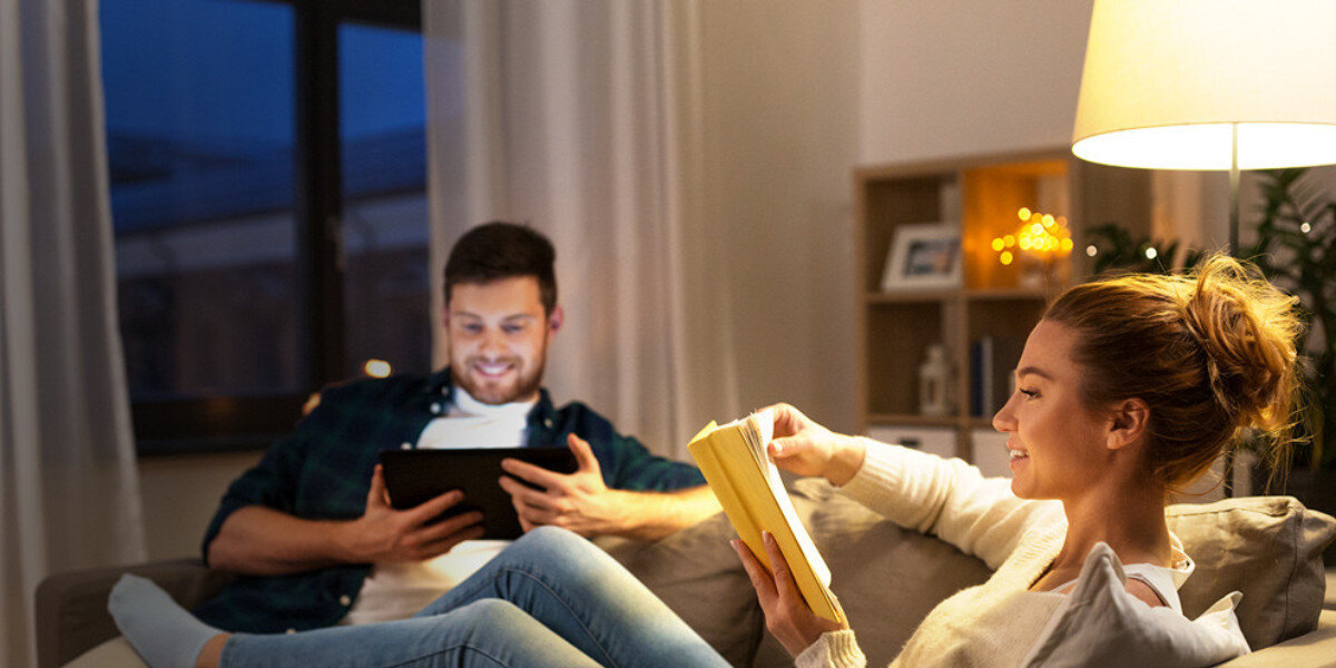 Inteligentna żarówka LED TP-LINK Tapo L535E 8.6W E27 Wi-Fi, RGB, temperatura, personalizacja, komfort, Para odpoczywa w salonie przy ciepłym świetle.