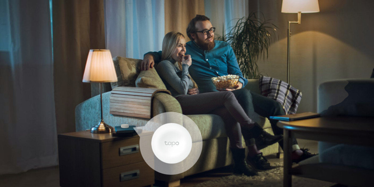 Inteligentna żarówka LED TP-LINK Tapo L535E 8.6W E27 Wi-Fi, Bezpieczeństwo, symulacja, tryb, zdalnie, Wieczorny relaks pary przed telewizorem w salonie.