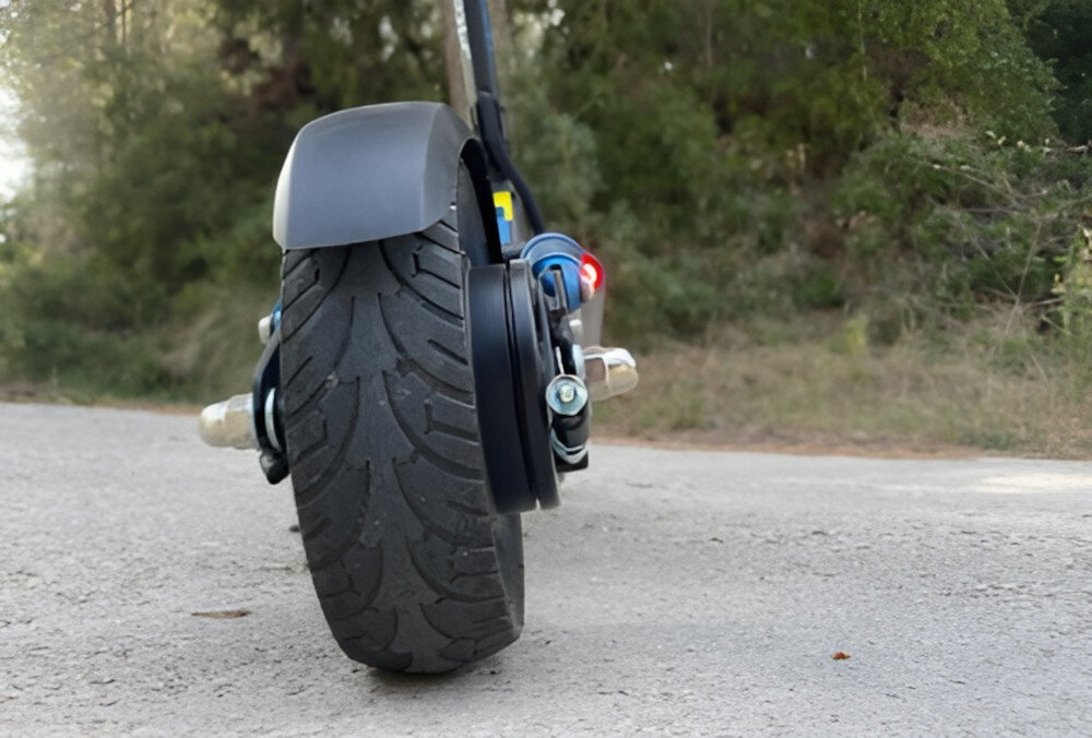 Hulajnoga elektryczna SKATEFLASH Echo 40km 350W 8 cali Czarny droga las w zbliżenie na tylne koło w tle drzewa krzewy 10-calowe koła dętkowe komfort i stabilność jazdy ułatwiają pokonywanie nierówności dętkowa konstrukcja lepsza amortyzacja v kontrola