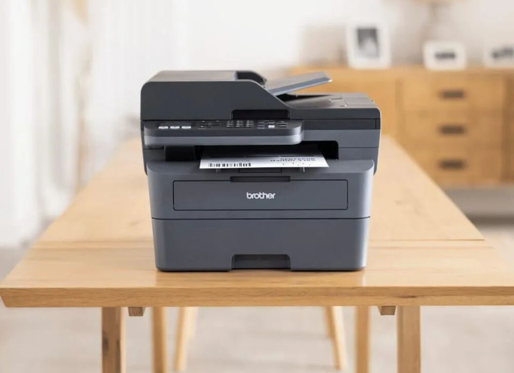 Urządzenie wielofunkcyjne BROTHER MFC-L2802DN Automatyczny druk dwustronny urządzenie postawione na drewnianym stole prędkość druku tryb monochromatyczny eliminacja długiego czasu oszekiwania czas potrzebny na wydruk pierwszej strony