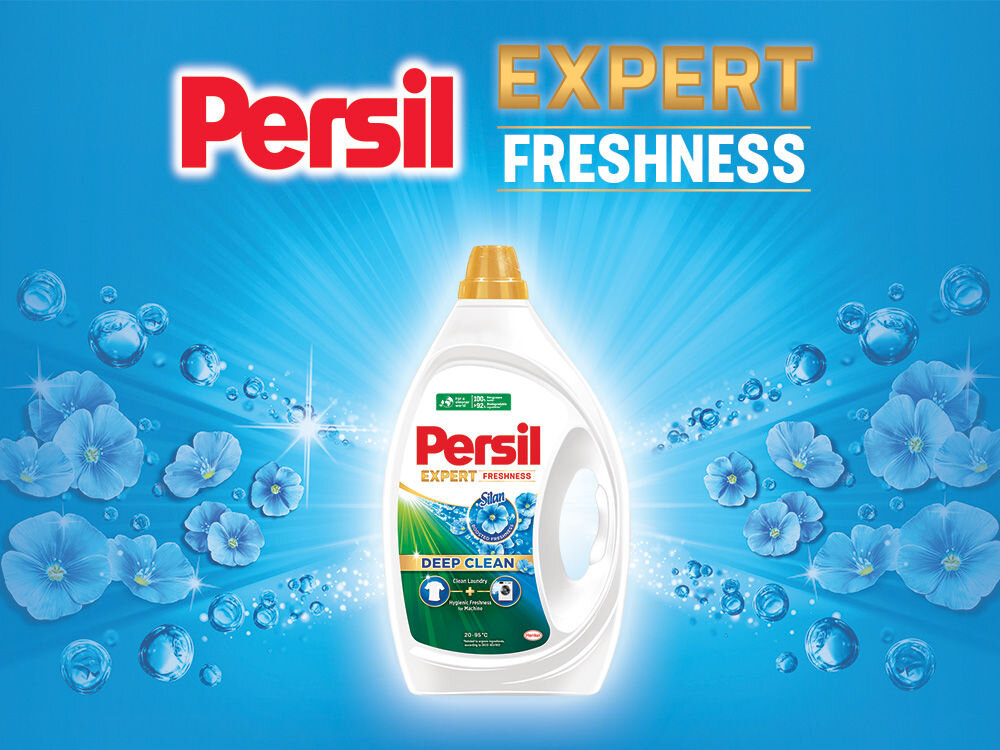 Żel do prania PERSIL PERSIL Reklama żelu Persil Expert Freshness. Duża butelka żelu na niebieskim tle z promieniami światła i pływającymi kwiatami, symbolizującymi świeżość. Widoczny opis: Deep Clean Laundry.