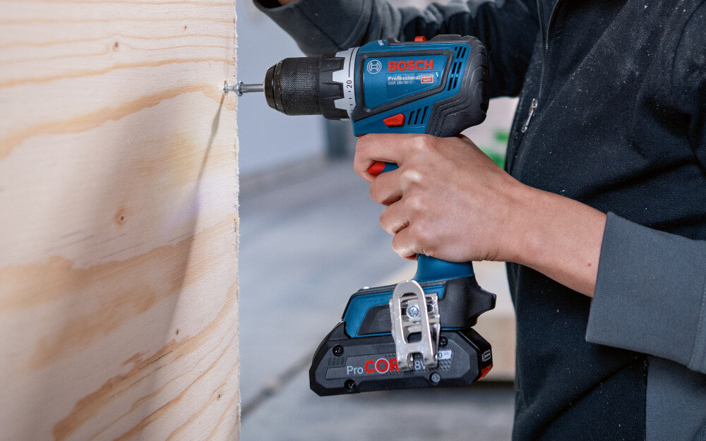 Wiertarko-wkrętarka BOSCH GSR 18V-90 FC Professional (06019K6203) pomieszczenie drewniana ściana osoba przykręca śrubę do ściany wszechstronność w pracy do wiercenia do wkręcania wydajność mobilność