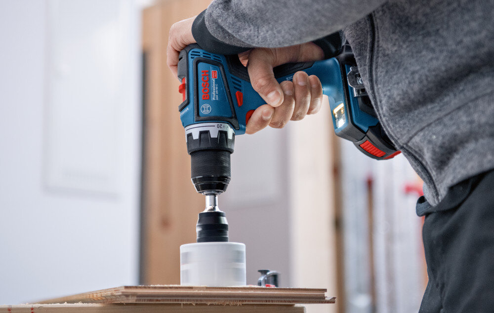 Wiertarko-wkrętarka BOSCH GSR 18V-90 FC Professional (06019K6200) pomieszczenie osoba wierci otwór w drewnianej desce specjalny system ochronny elektroniczna ochrona ogniw ECP zabezpiecza akumulator przed przegrzaniem i przeciążeniem baterie zachowują pełną wydajność przez dłuższy czas