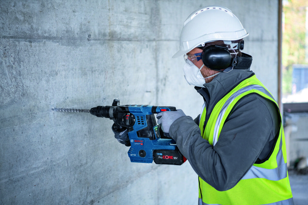 BOSCH GBH 18V-28 C - Mężczyzna używa akumulatorowego młota udarowo-obrotowego do wiercenia w betonie.