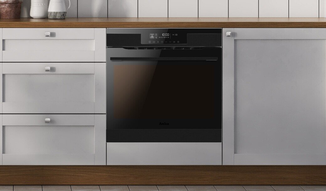 Włączone oświetlenie w urządzeniu marki Amica; piekarnik w jasnej zabudowie kuchennej z uchwytami