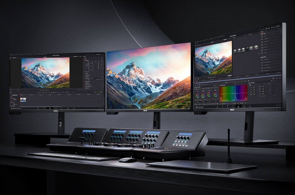 Monitor ASUS ProArt PA32UCXR Trzy monitory ustawione obok siebie na biurku z czarnym panelem sterowania do edycji wideo. Na ekranach wyświetlane są obrazy górskiego krajobrazu oraz interfejsy programu do obróbki filmów, opis