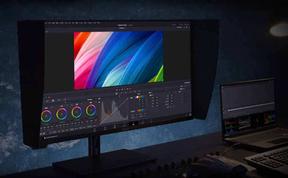 Monitor ASUS ProArt PA32UCXR Monitor z zamontowanymi osłonami przeciwodblaskowymi na biurku w ciemnym pomieszczeniu. Na ekranie wyświetlony jest program do edycji kolorów z kolorową grafiką w centrum, głośniki, audio, moc, dźwięk