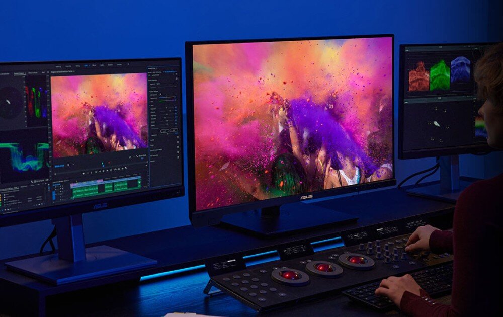 Monitor ASUS ProArt PA32UCXR Osoba pracująca przy stanowisku edycji wideo z trzema monitorami, na których wyświetlane są narzędzia do korekcji barw oraz scena z intensywnymi kolorami, kolory, odwzorowanie, głębia kolorów