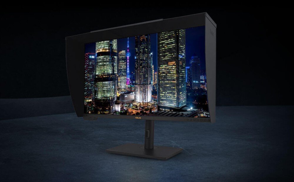 Monitor ASUS ProArt PA32UCXR Monitor z zamontowanymi osłonami przeciwodblaskowymi na czarnym tle. Na ekranie widoczna panorama miasta nocą z oświetlonymi drapaczami chmur, standardy HDR, certyfikat