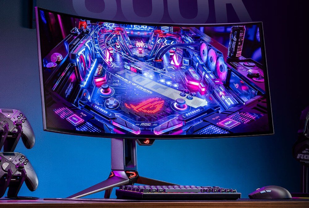 Monitor ASUS ROG Swift PG34WCDM Monitor na biurku w przyciemnionym pomieszczeniu, wyświetlający grafikę w stylu neonowego pinballa z elementami nawiązującymi do sprzętu komputerowego, czas reakcji, odświeżanie, płynność, synchronizacja FreeSync i G-SYNC