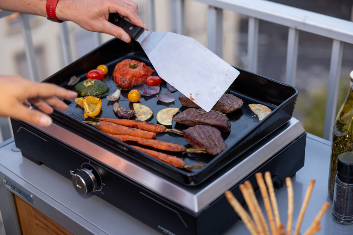Grill elektryczny CAMPINGAZ Plancha Electric, składniki, różnorodne, grillowanie, płyta, zbliżenie na płytę grilla na którym są różnego rodzaju produkty