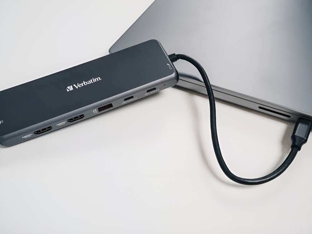 Hub Verbatim 32153 Zbliżenie na hub podłączony do laptopa leżący na białej powierzchni,
hub technologia adapter laptop komputer
