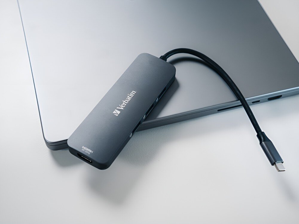 Hub Verbatim 32151 Adapter z logo Verbatim z przewodem USB-C leży na zamkniętym laptopie o metalicznej obudowie,
hub technologia adapter laptop komputer