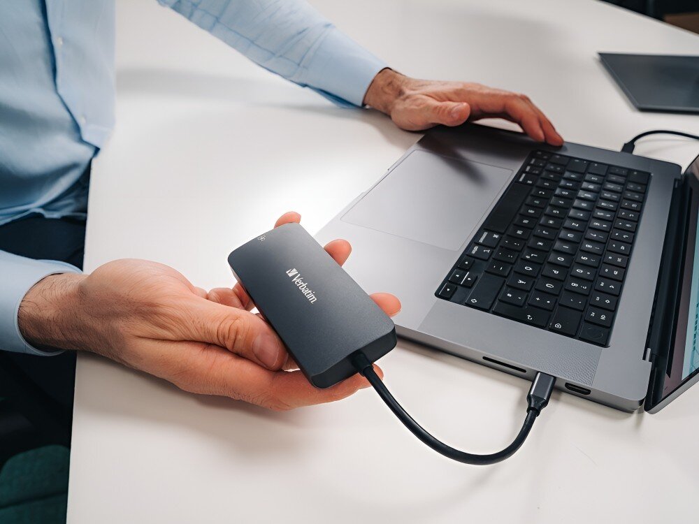 Hub Verbatim 32150 Osoba trzyma adapter z logo Verbatim, który jest podłączony do laptopa przez przewód USB-C,
hub gadżet technologia laptop komputer