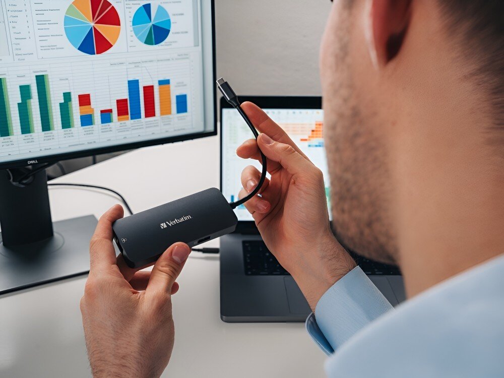 Hub Verbatim 32150 Mężczyzna patrzący na monitor z kolorowymi wykresami, trzyma w rękach adapter z przewodem USB-C,
hub sterowniki port usbc kompatybilność funkcjonalność