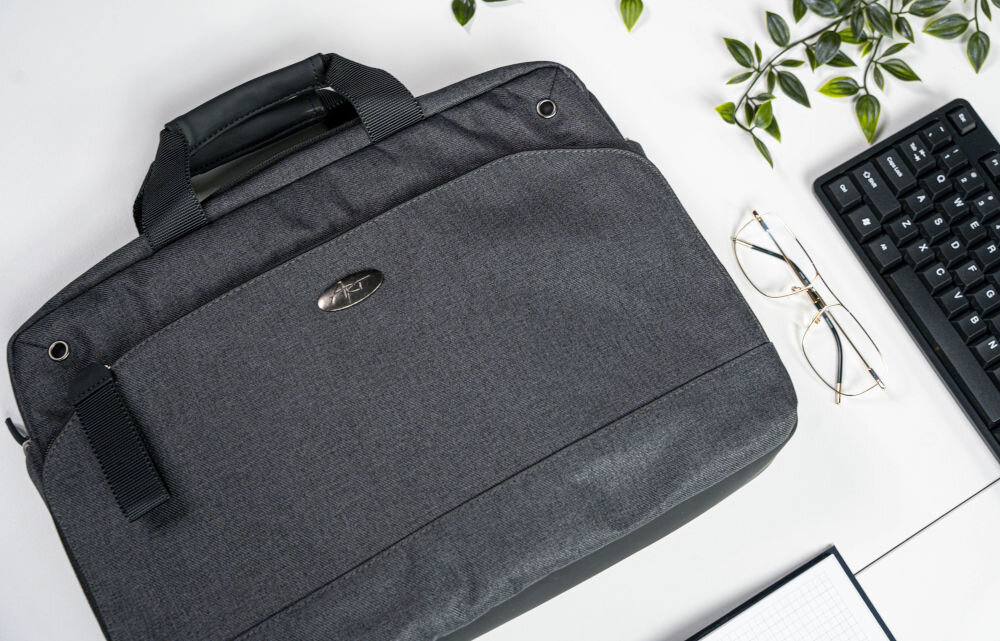 Torba na laptopa ART NB-0362 15.6 cali prezentacja torby na białym biurku obok okulary klawiatura roślina i otwarty notes materiał łatwy do czyszczenia odporna na zabrudzenia
