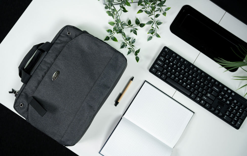 Torba na laptopa ART NB-0362 15.6 cali prezentacja torby na białym biurku obok długopis klawiatura roślina i otwarty notes torba do różnych zastosowań etui na dokumenty tablety książki