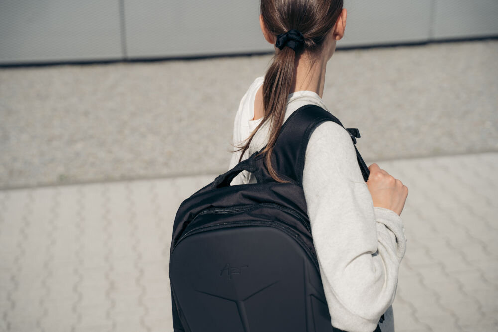 Plecak na laptopa ART BP-8948 15.6 cali prezentacja plecaka założonego na plecy kobiety widoczny uchwyt w tle szklany budynek górny uchwyt transport wygodne noszenie w dłoni