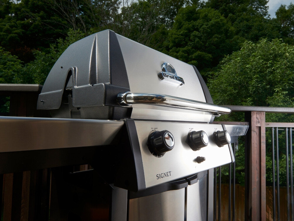 Grill gazowy BROIL KING Signet™ 320 11.4 kW 65 x 38 + 60 x 26 cm ogród zbliżenie na pokrywę grilla widoczna nazwa i logo grilla solidna konstrukcja ze stali szlachetnej trwałość elegancki wygląd ruszt główny o wymiarach 65 x 38 cm górną półkę o wymiarach 60 x 26 cm do podgrzewania potraw grillowania pośredniego wolnego dopiekania mięs