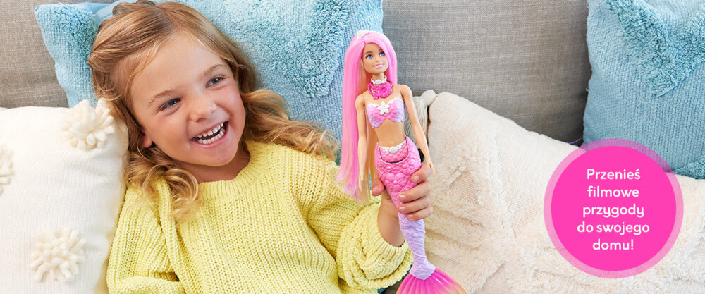 Dziewczynka trzymająca lalkę Barbie, obok widoczny jest napis 'Przenieś filmowe przygody do swojego domu!'.