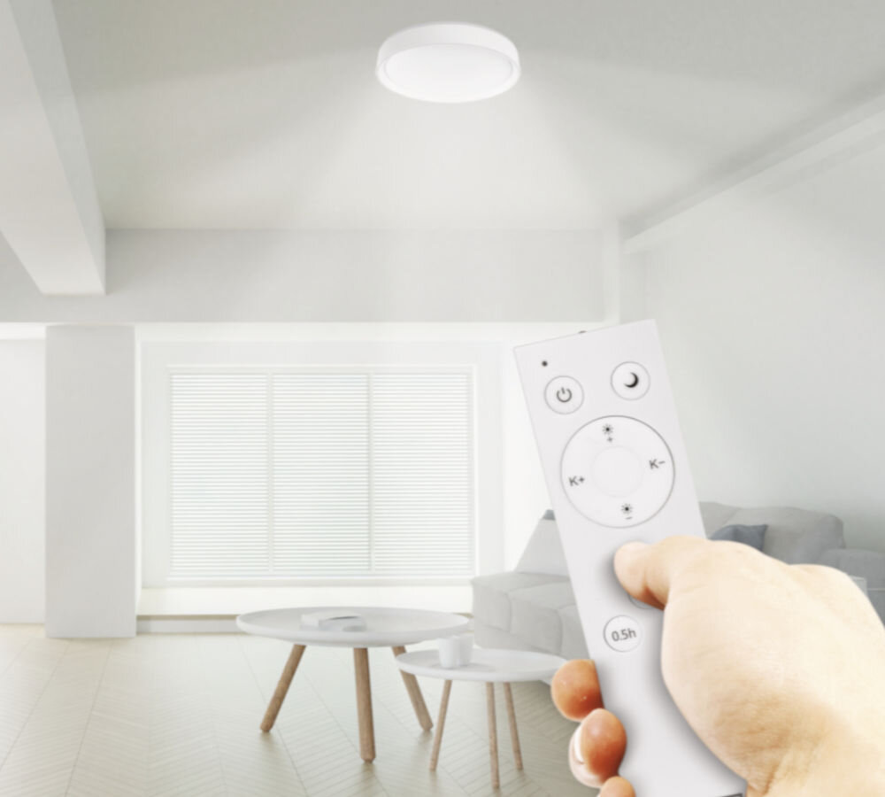 Oprawa natynkowa EMOS GoSmart ILVI 45W LED z pilotem, regulacja, barwa, temperatura, synchronizacja, dłoń trzyma pilot w ręku i steruje oświetleniem w pokoju