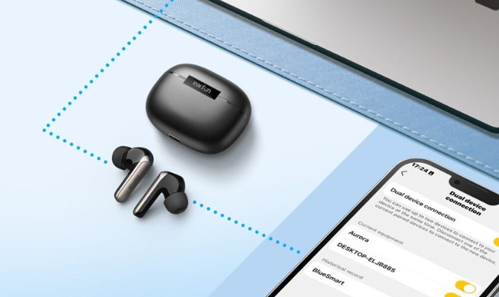Słuchawki dokanałowe EARFUN Air 2 NC multipoint dwa urządzenia Bluetooth przełączanie laptop smartfon, słuchawki z etui ładującym oraz smartfonem leżace na blacie