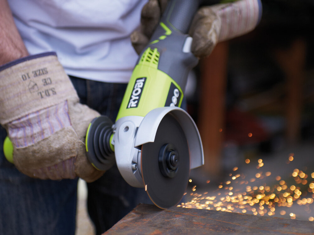 Szlifierka kątowa RYOBI R18AG-120S osoba trzyma szlifierkę tnie metalowy element do cięcia i szlifowania mobilność zasilanie akumulatorowe mocna efektywna ergonomiczna budowa