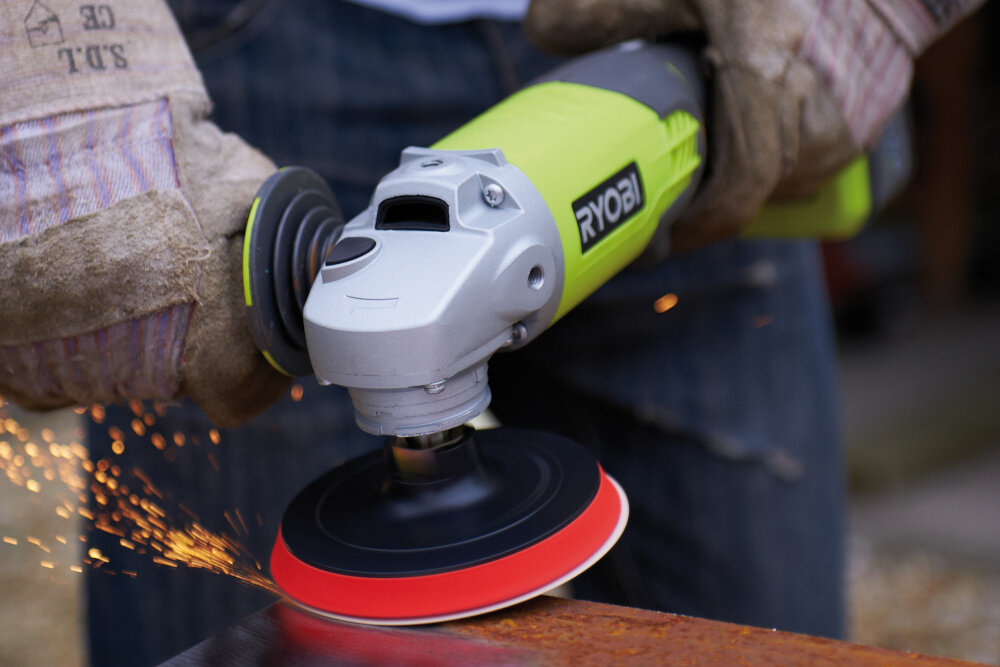 Szlifierka kątowa RYOBI R18AG-120S osoba trzyma szlifierkę szlifuje metalowy element iskry prędkość do 7500 obr./min szybkie tempo pracy efektywne usuwanie naddatków materiału średnica tarczy 115 mm