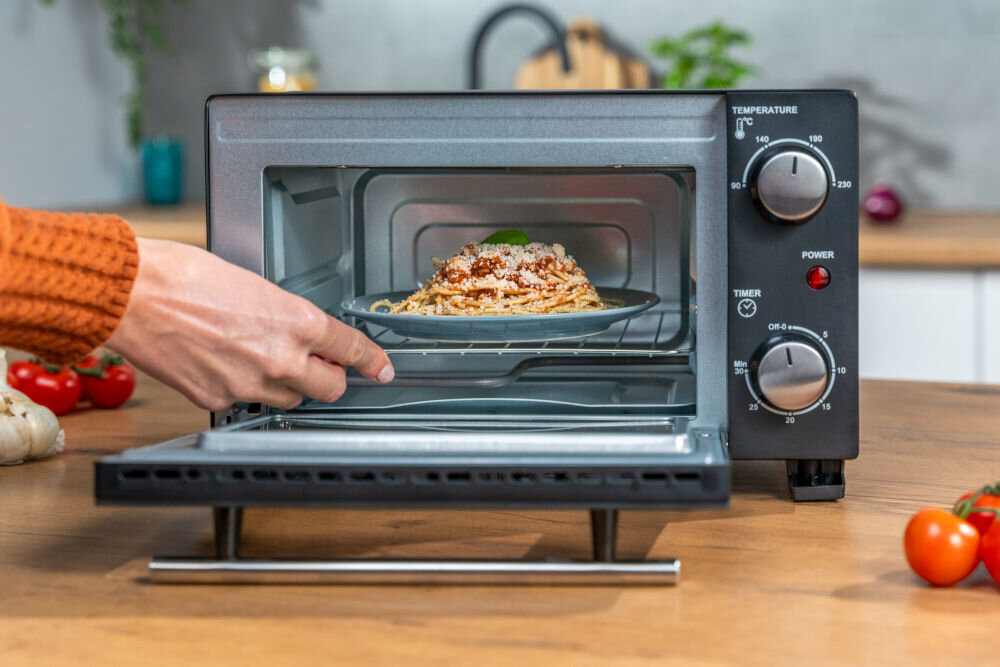 Piekarnik GOTZE & JENSEN MP210 otwarty piekarnik z daniem na talerzu widocznym w środku na dnie widoczna tacka na okruchy