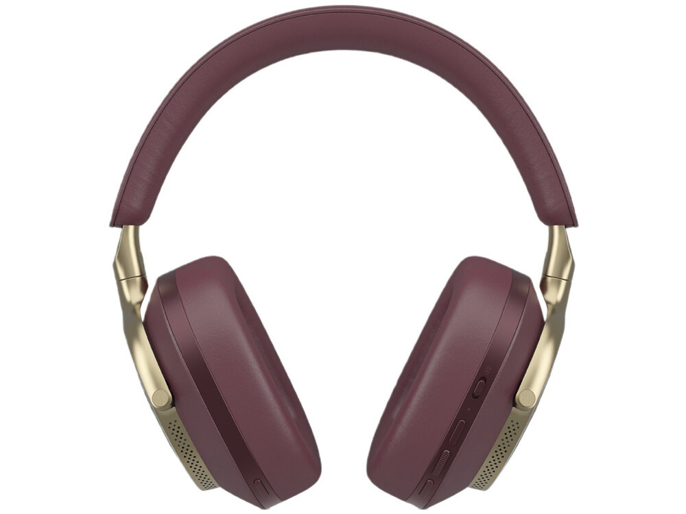 Osoba nosi nauszne słuchawki w ciemnym kolorze, z widocznym logo BOWERS_WILKINS & Wilkins. W tle ceglana ściana i roślinność.