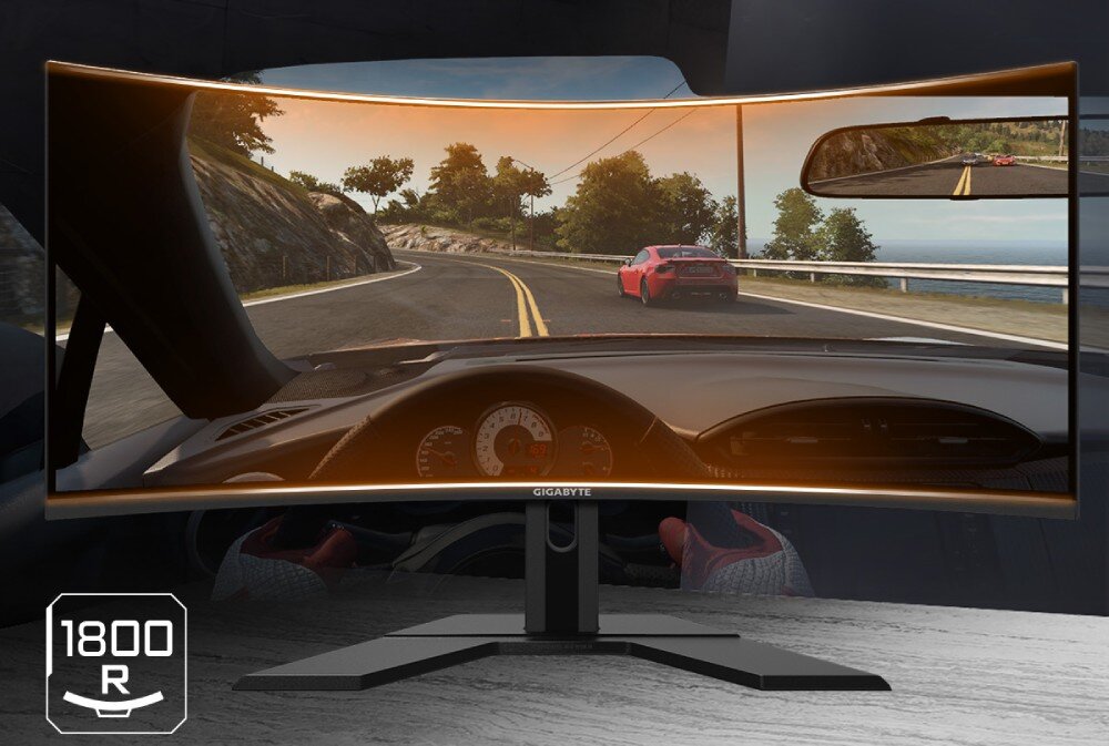 Monitor GIGABYTE AORUS CO49DQ Monitor wyświetlający widok z gry wyścigowej z perspektywy kierowcy. Ekran ma zakrzywiony kształt, a w dolnym rogu znajduje się ikona z napisem '1800R', przekątna, proporcje, zakrzywienie