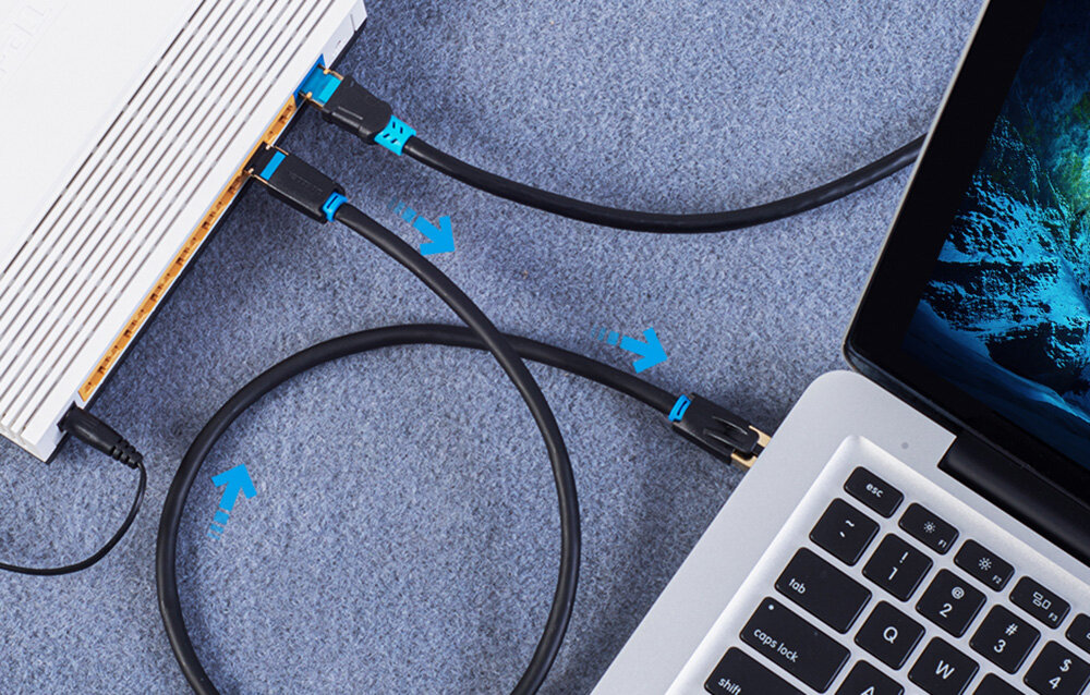 Na obrazie widać czarny kabel sieciowy podłączony do laptopa i innego urządzenia. Na kablu znajdują się niebieskie oznaczenia i strzałki wskazujące kierunek połączenia.