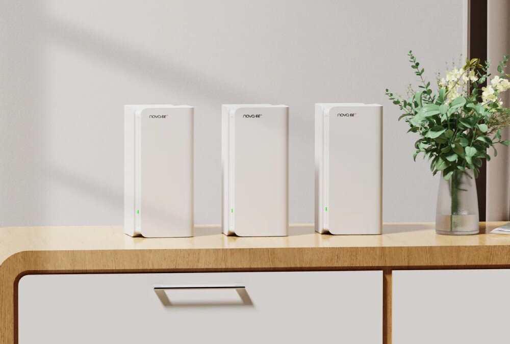 Router TENDA MX21 Pro Trzy białe routery mesh ustawione w rzędzie na jasnej drewnianej komodzie z zielonymi diodami LED świecącymi z przodu urządzeń