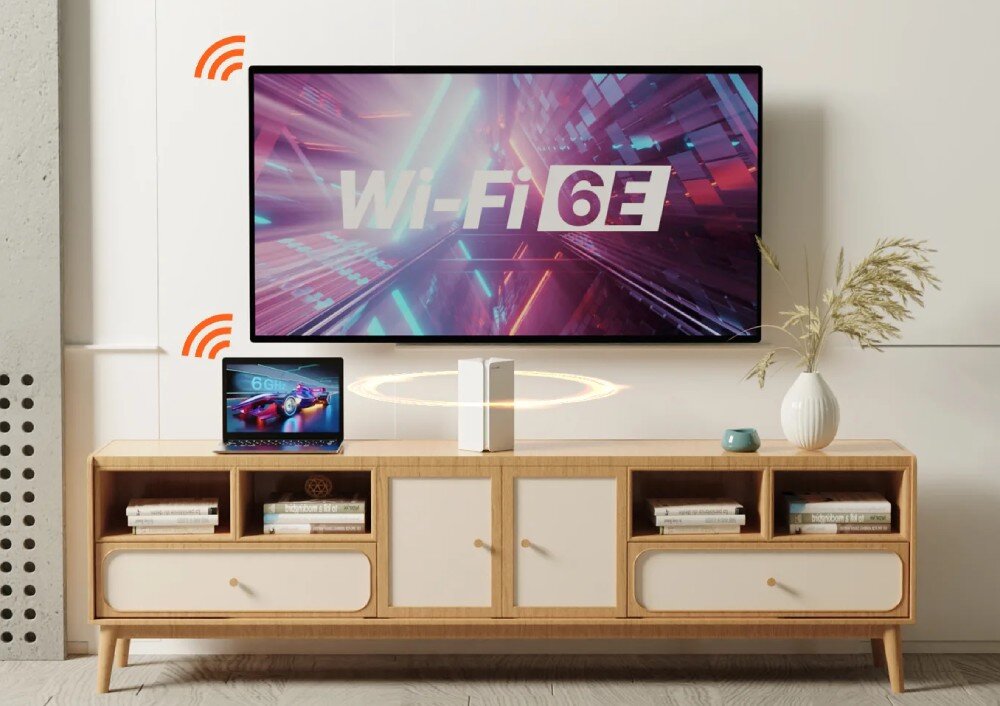 Router TENDA MX21 Pro Telewizor zamontowany na ścianie nad drewnianą szafką RTV z routerem mesh pośrodku, wyświetlający napis 'Wi-Fi 6E' i ikony sygnału bezprzewodowego łączące urządzenia