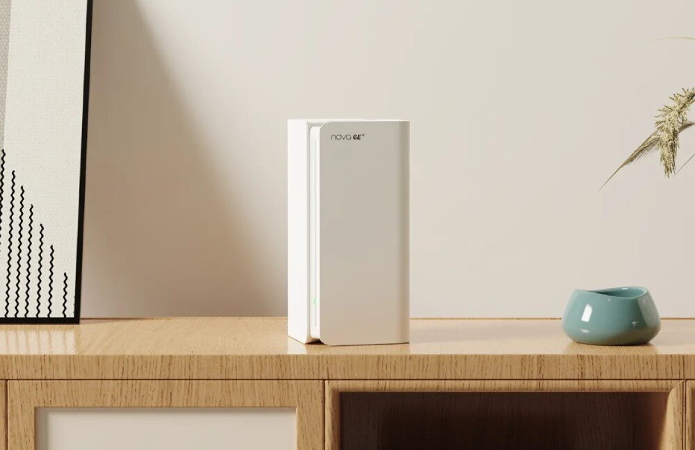 Router TENDA MX21 Pro Pojedynczy biały router mesh w pionowej obudowie stojący na drewnianej półce obok turkusowej ceramicznej doniczki